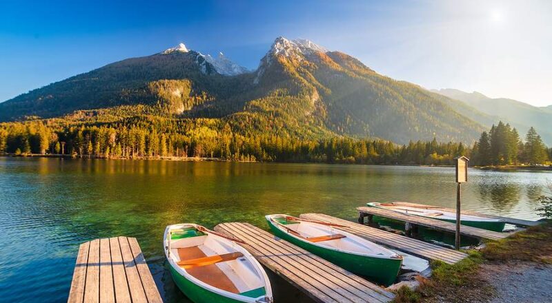 bateaux amarrés au bord d'un lac en automne, montagne à l'horizon